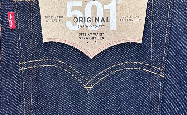 Close-up of the back patch label on a pair of Levi's 501 original shrink-to-fit jeans, serving as a guide to the brand and fit style.