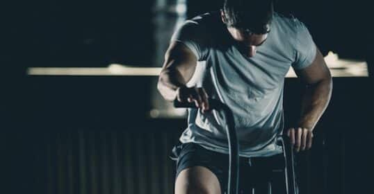 Man intensely following his HIIT routine on an air bike in a gym setting.