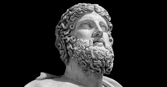 Marble bust of a bearded man with curly hair, sculpted in classical Greek or Roman style, embodying timeless manliness, set against a black background.