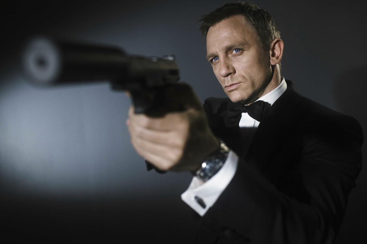 Daniel Craig give posing with gun.