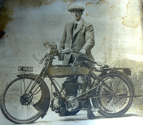 Vintage man standing with motorbike.