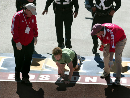 A man crawling in boston marathon to finish line across the team. 