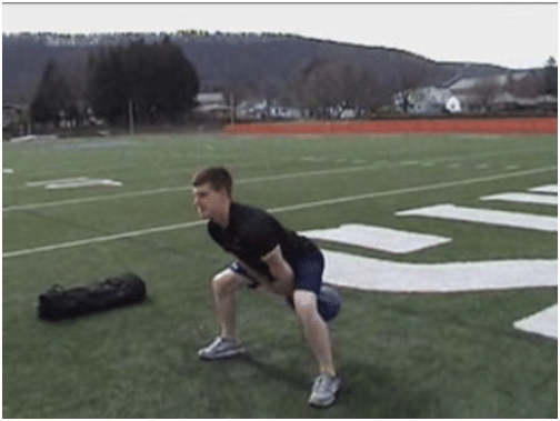 Man doing exercise by pulling down kettlebell in ground. 