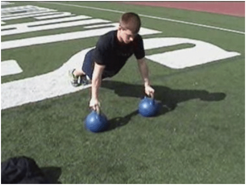 Man doing kettlebell push up in the ground.