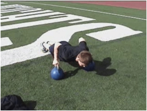 Man doing kettlebell push up in the ground.