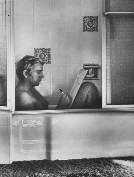 Vintage man writing on paper in the bathtub.