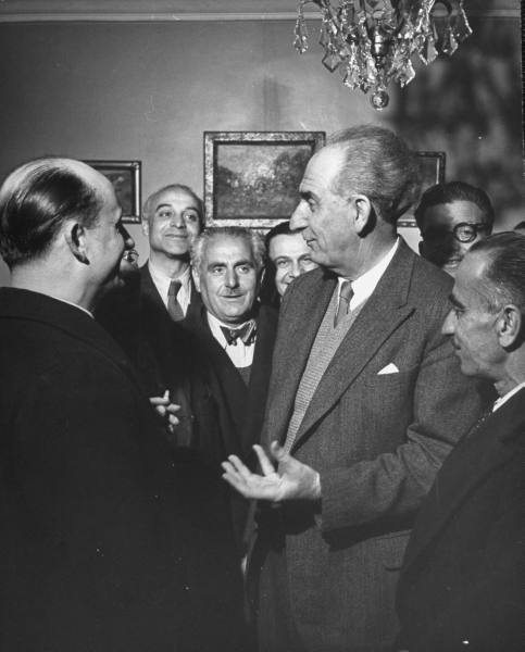 Gathering of men in party commanding a room and talking.