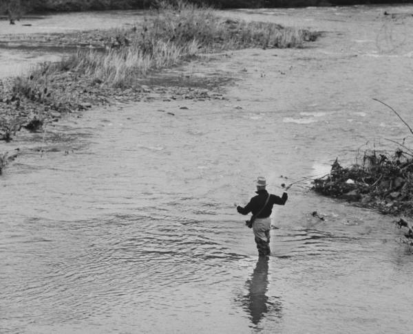 Vintage man doing fly fishing while standing in the river.