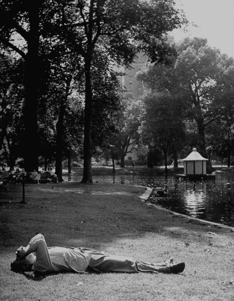 Vintage man lying on grass in the park near the lake.