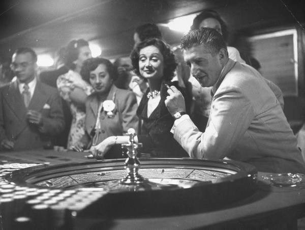 Vintage men playing roulette game in casino.