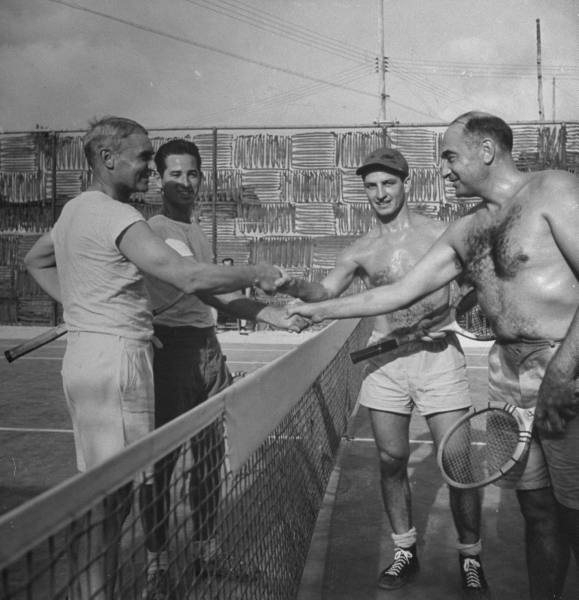 Vintage tennis players shaking hands in the playing area.