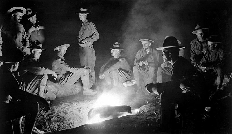 Vintage cowboys sitting around the campfire.