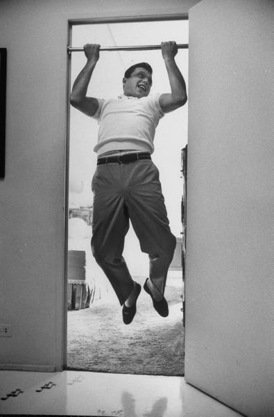 Vintage man enjoying while doing pull ups in doorway.