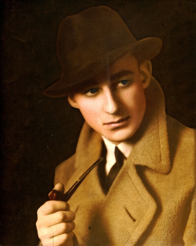 Vintage young man's portrait with a hat and overcoat while smoking pipe in his hand.