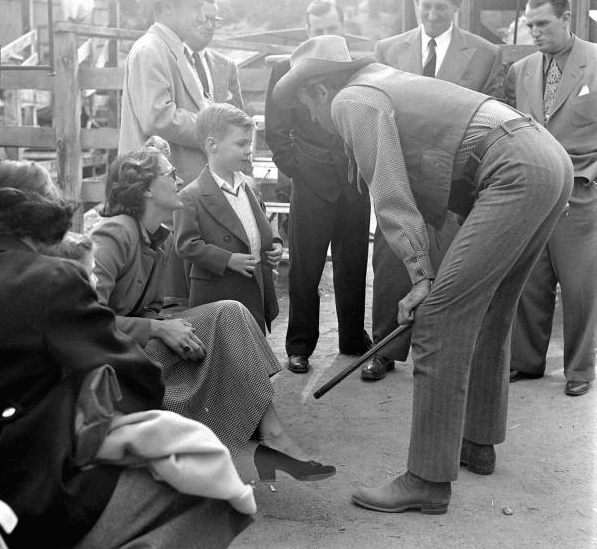 Jimmy Stewart wearing cowboy hat talking to a young boy.