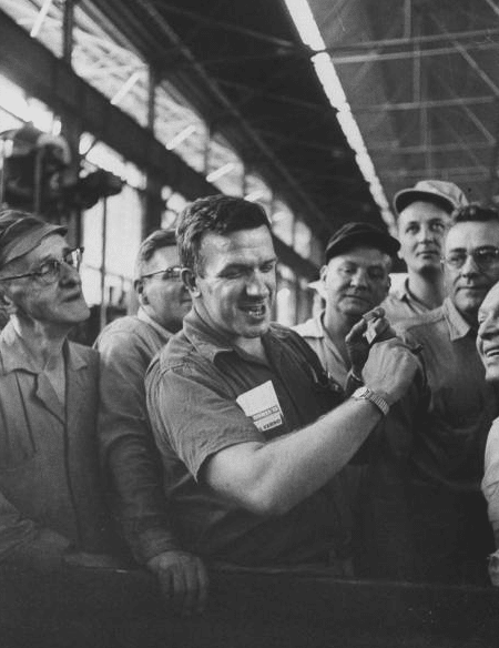 Worker smiling while watching his watch in front of other workers.