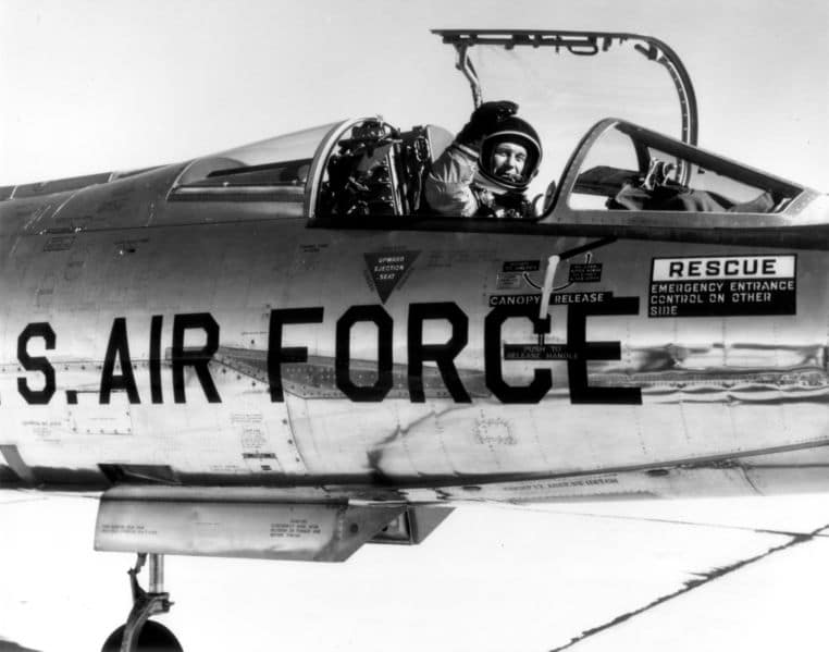 Vintage Chuck Yeager waving while sitting in cockpit.