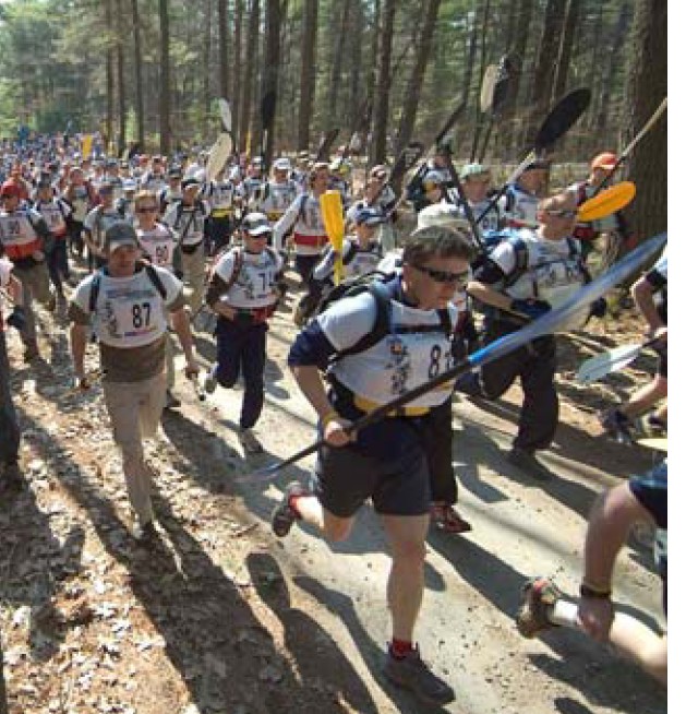 Men enjoying adventure racing and holding paddles.