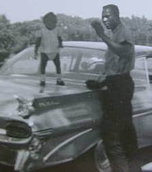 Vintage father posing with son standing on car.