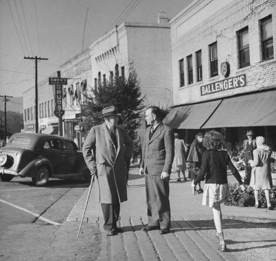 Vintage men walking and talking on sidewalk downtown. 