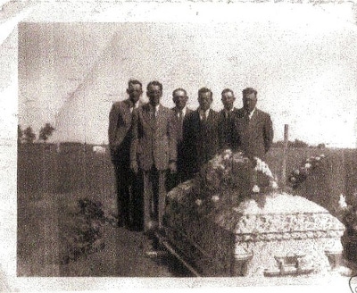 Gentlemen attending funeral at graveyard.