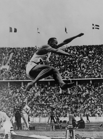 Jesse Owens black white long jump and crowd audience in background.