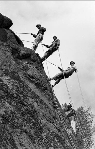 Vintage men climbing on mountain with ropes cliff.