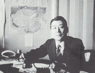 Chiune Sugihara sitting at desk and holding pen.