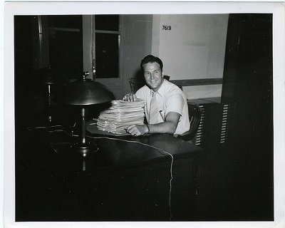 Vintage man at desk with pile of paperwork.