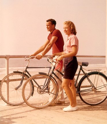 Vintage couple doing cycling on a beach side.