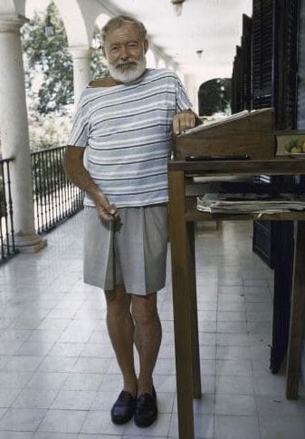 Ernest Hemingway older man with standing desk in shorts and sock-less.