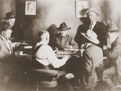 Vintage men cowboys playing poker game while smoking cigars.