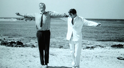 Actors standing on a sea site in Zorba the greek dance ending of movie.