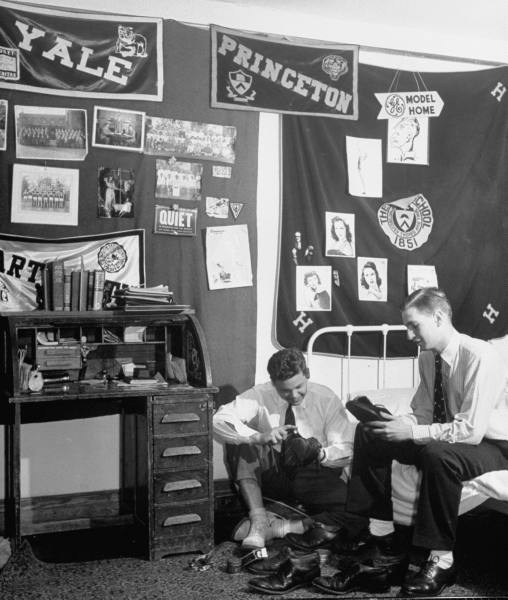 Vintage college men Polishing shoes in dorm room.