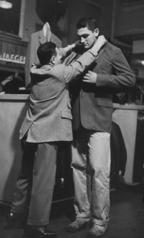 Vintage man helping another man to wear a blazer.