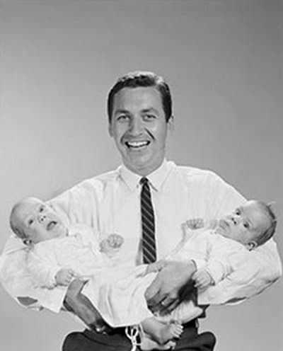 Vintage father holding newborns twins.