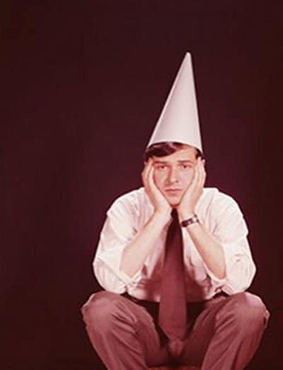 Vintage man squatting in dunce cap.