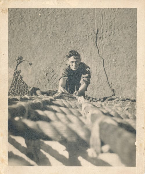 A boy climbing on the rope ladder.