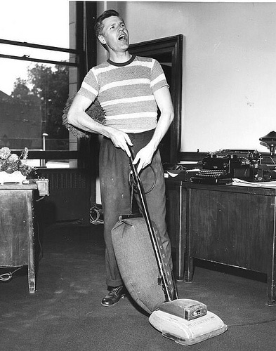 Vintage man vacuuming for floor cleaning. 