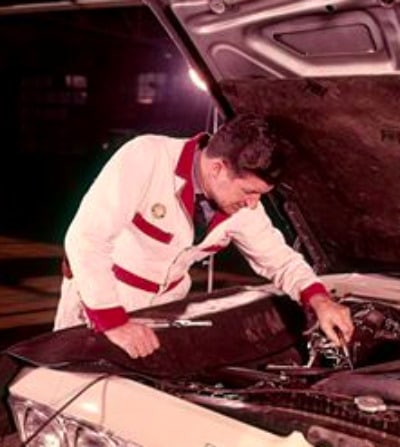 Vintage mechanic working under car hood.