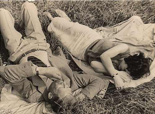 Vintage couple laying on blankets on the grass.