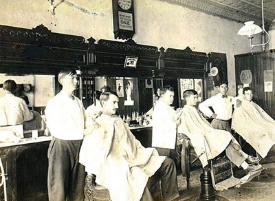 Vintage men getting haircut at barbershop.