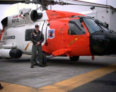 Adam Sustachek coast guard helicopter mechanic posing with helicopter. 