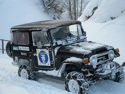 Toyota land cruiser driving in snow with offloading chains. 