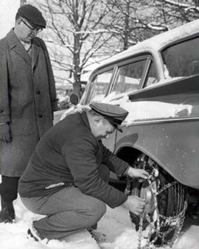 Driver removing chains from car in front of owner.