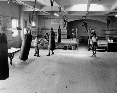 Boxer having practice session with trainer in gym.