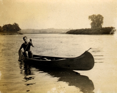 Vintage man canoeing on lake.