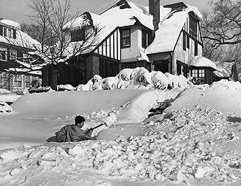 Vintage man doing snow shoveling in front of house.