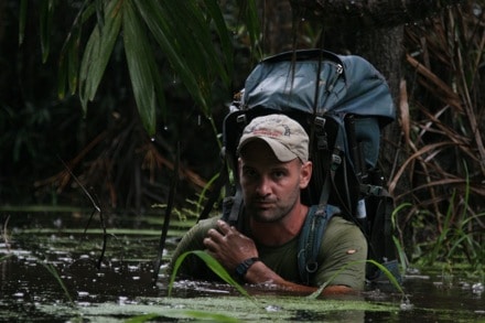 Ed Stafford dipping in amazon pond with bag.