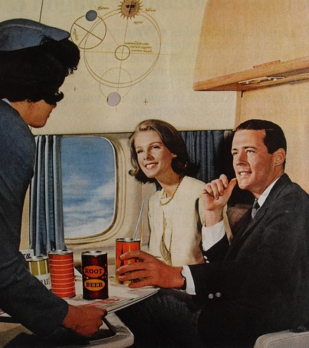 A man serving the drinks to coulple sitting in aeroplane. 